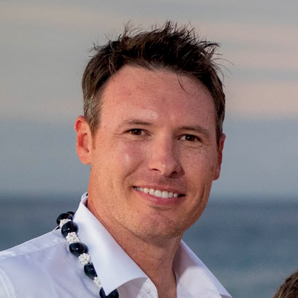 Brant Westover, a man with black hair, grins, with an ocean in the background.