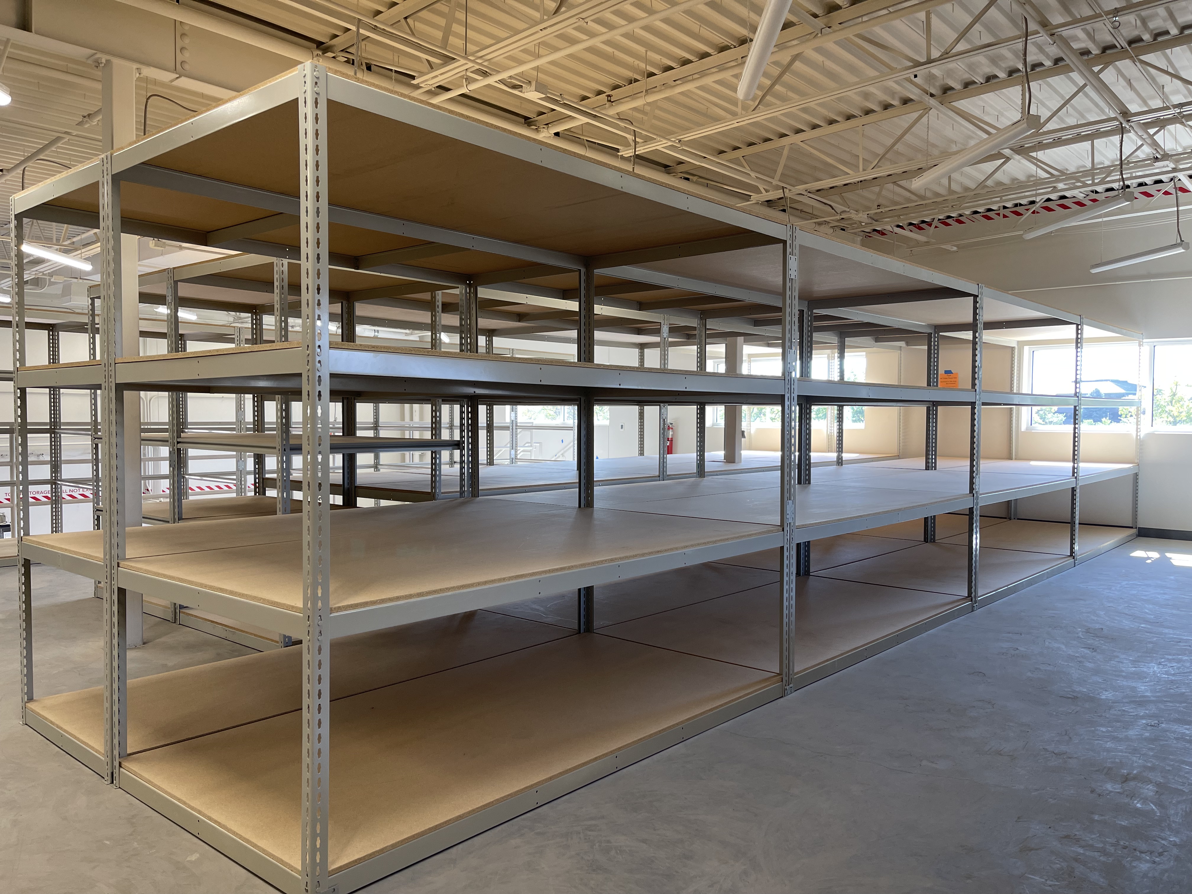 Numerous rows of boltless shelving, characterized by wood lying upon steel frames.
