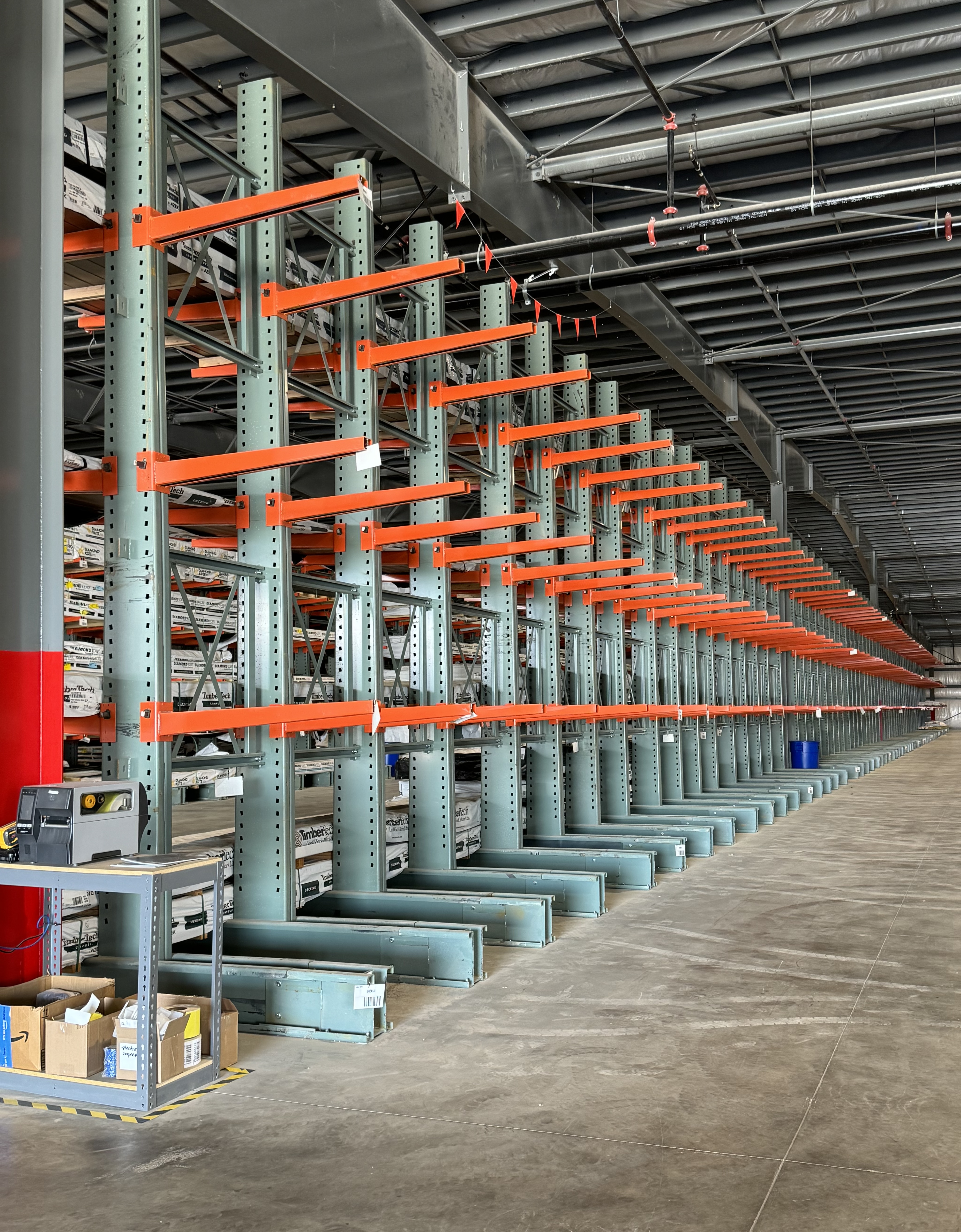 Long rows of cantilever racking with 3 to 4 levels of orange cantilever arms.