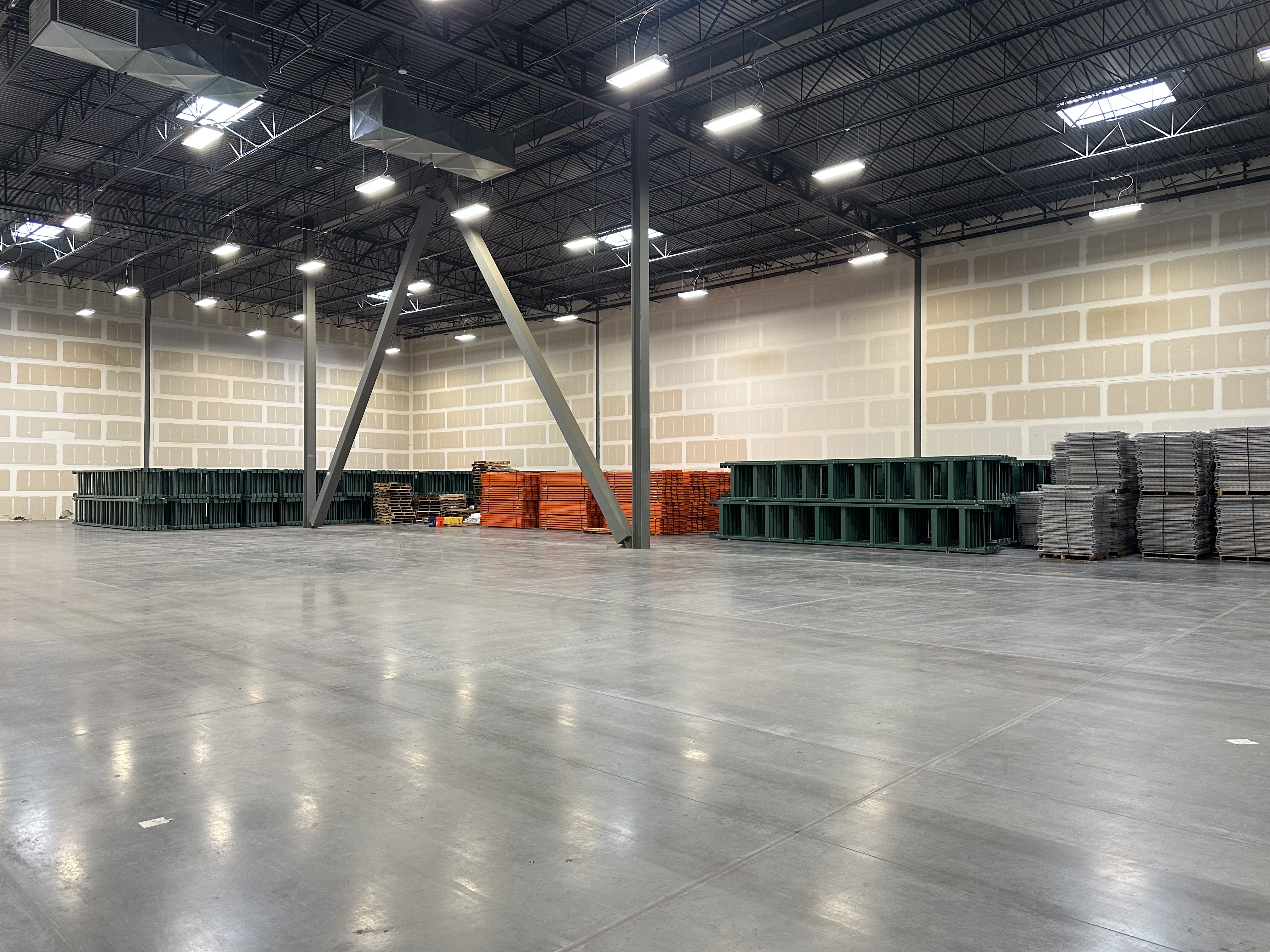 A warehouse with an empty floor and disassembled material placed neatly to the side.