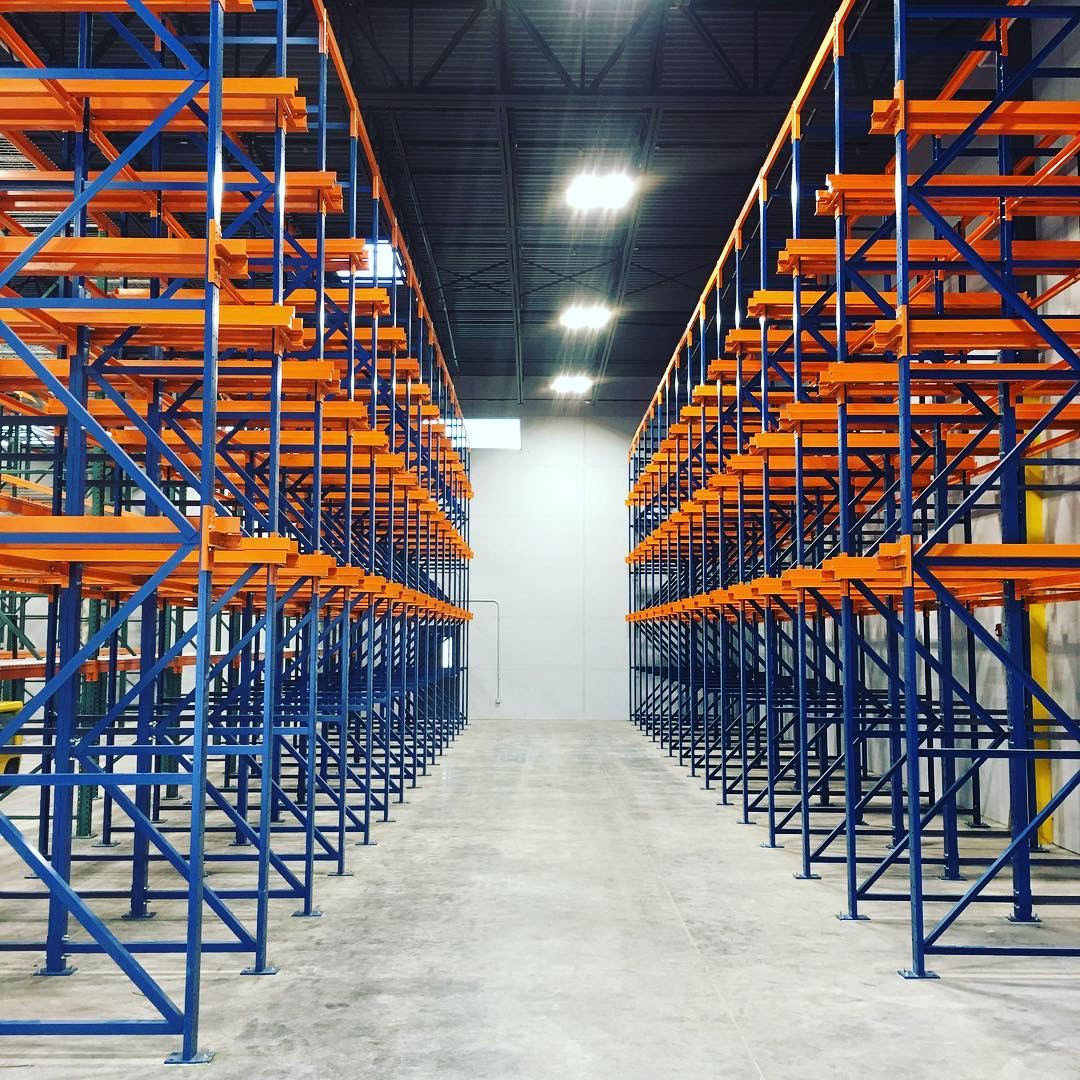 Rows of drive-in racks with blue uprights and orange rails.