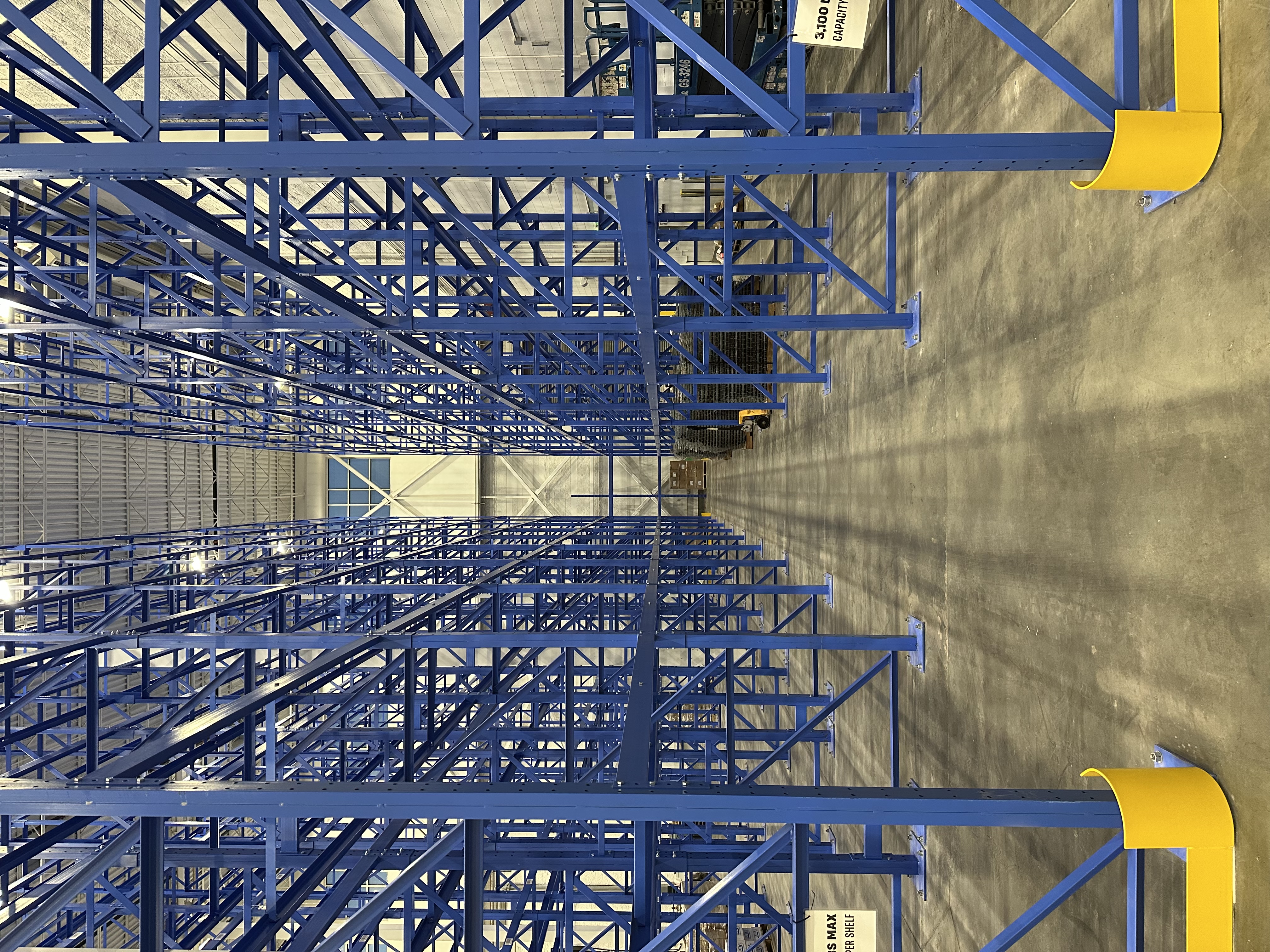 Sturdy blue uprights and beams composing massive structural pallet racks.